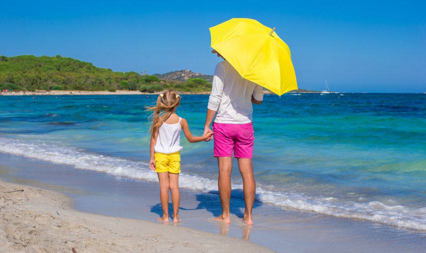 Two people hold hands on the beach