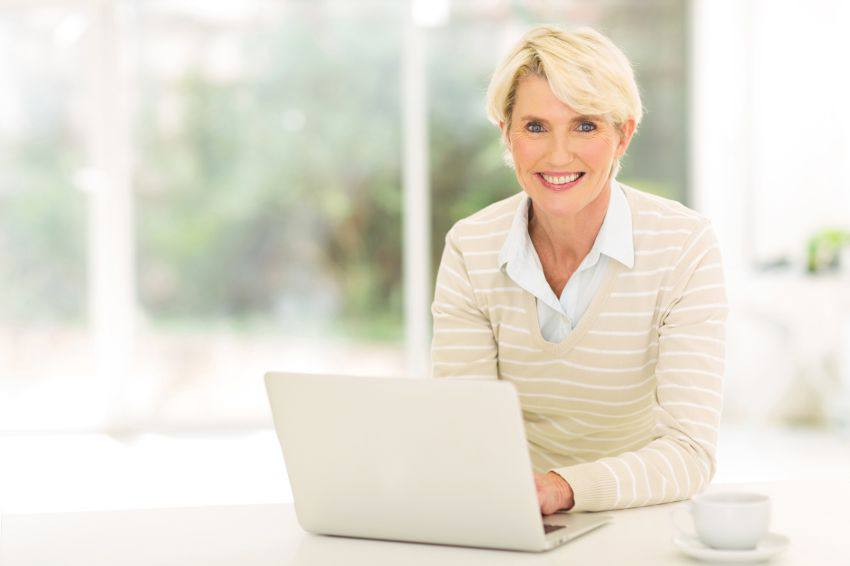 A woman smiling while using her laptop 