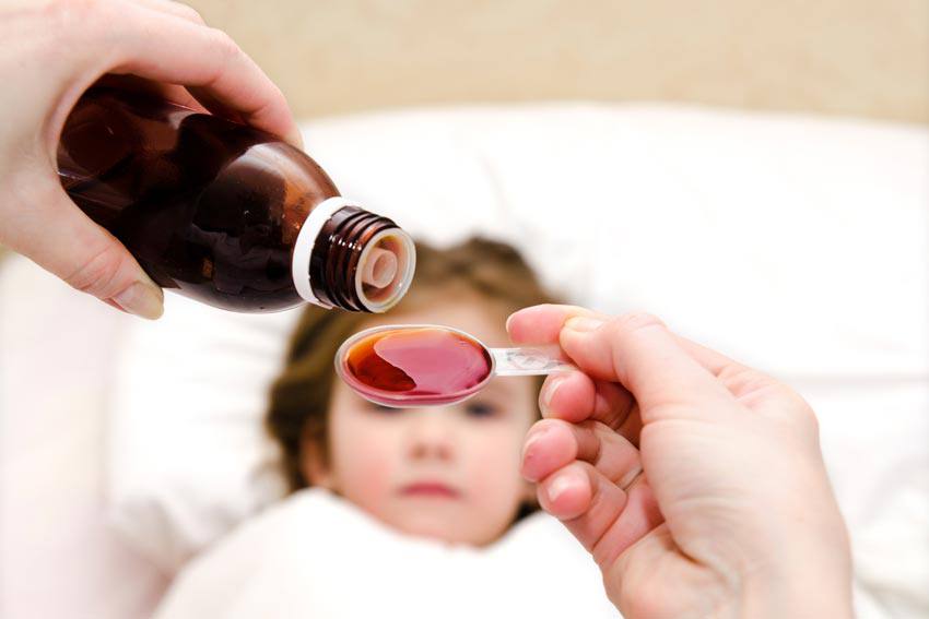 Medicine poured in a spoon in front of a sick child