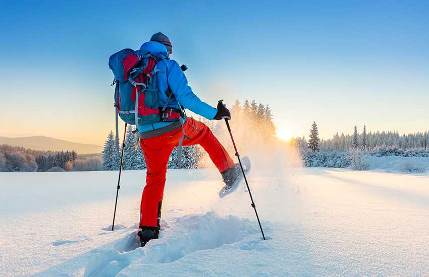 A person hiking in the snow with proper equipment