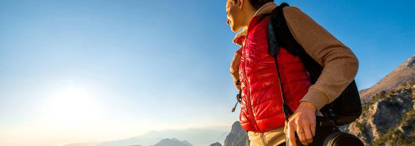 A woman hiking on a mountain looking at the sun