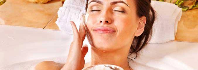 A woman applying a face mask while lying down