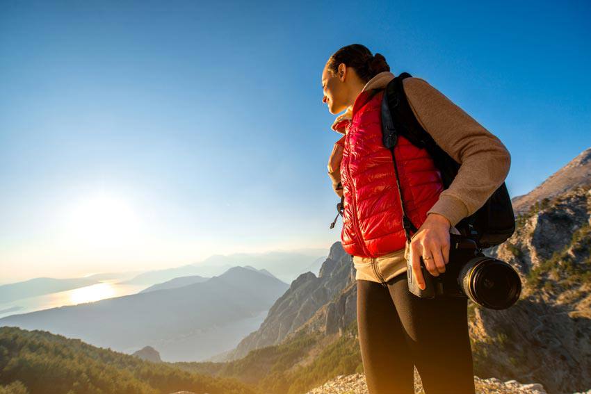 A woman hiking on a mountain looking at the sun