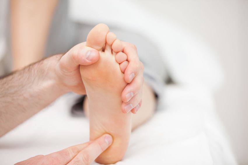 A person holding and pressing on the sole of another's foot