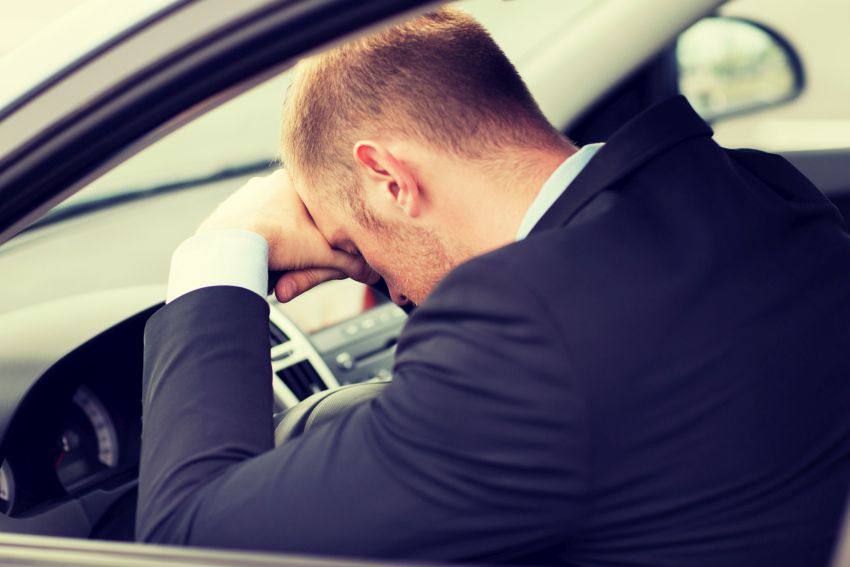 Man leaning head on stering wheel