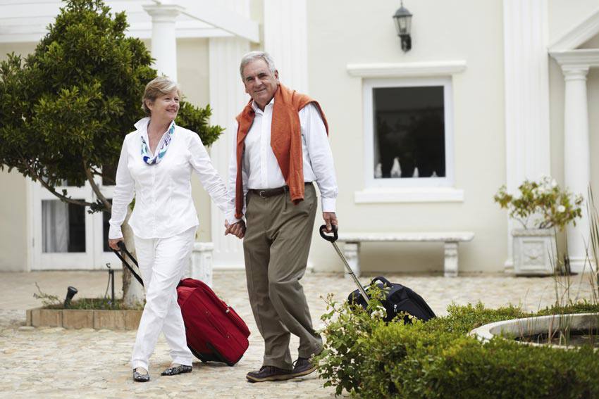 An elderly couple ready to travel with their suitcase