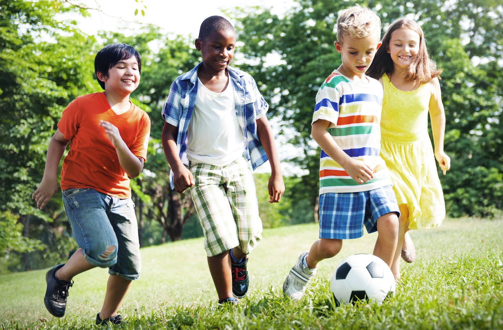 Four children playing soccer on a grass field