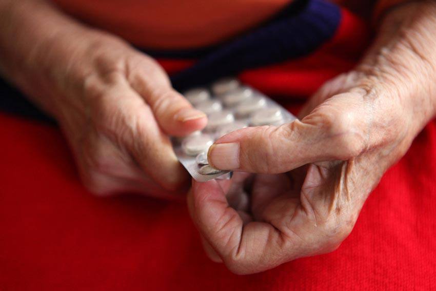 Elderly person takes pills