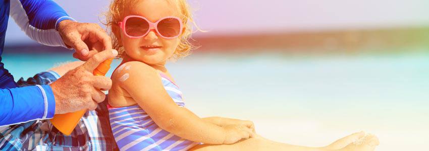 A parent applying sunscreen lotion on their child