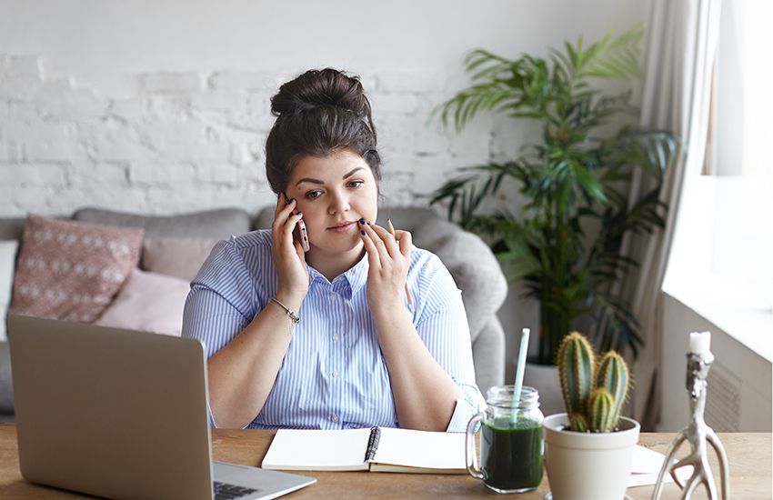 A woman talking on the phone in front of a computer