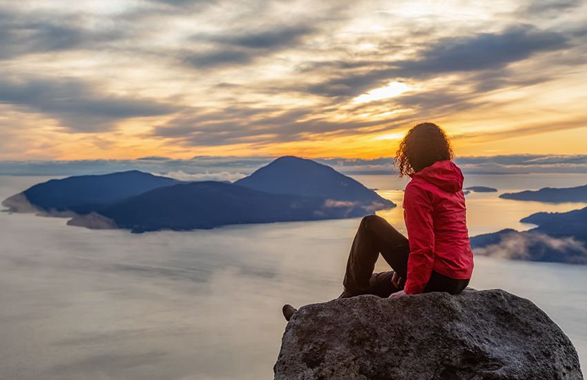 A woman sitting at the top of a mountain