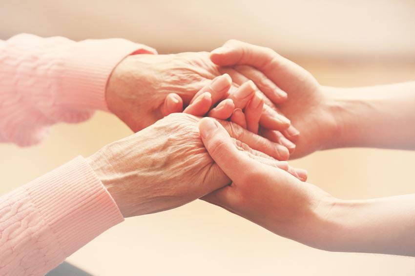 A young person holding the hands of an older person