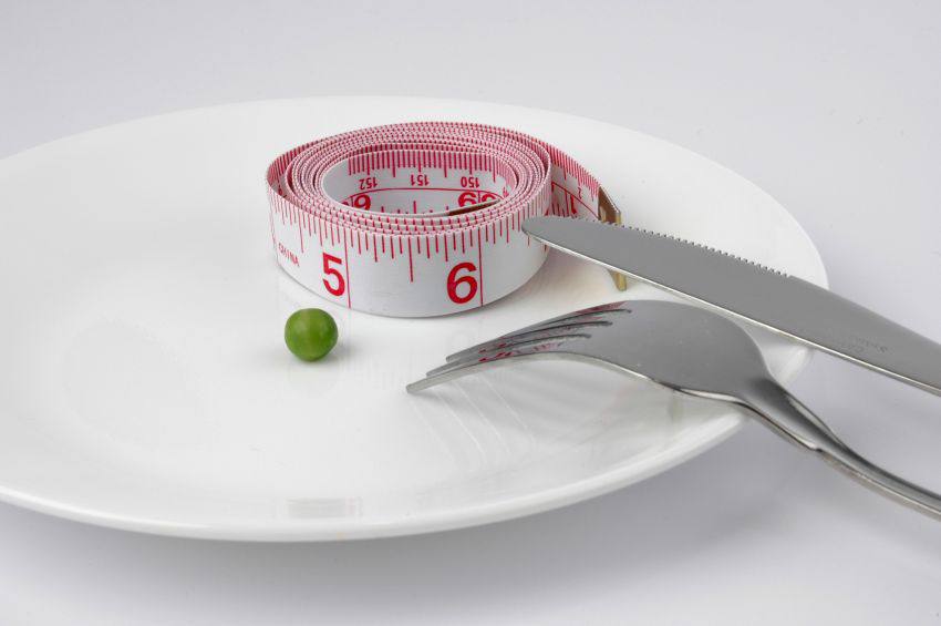 A plate with a tape measurer and a pea on it