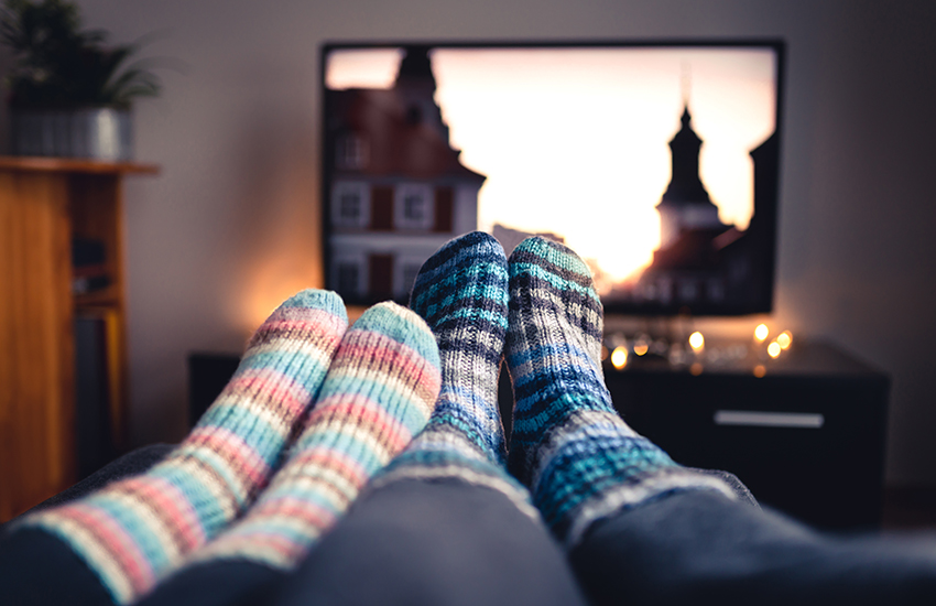 Two people watching television with their feet touching