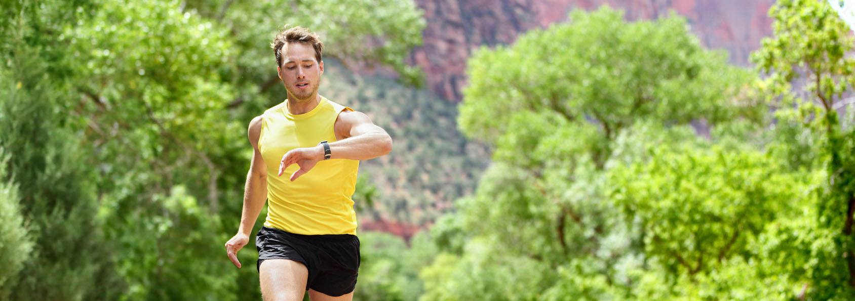 A man jogging on the road with a fitness tracker