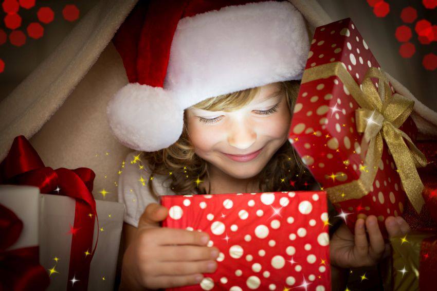 A child opening a christmas present under a blanket