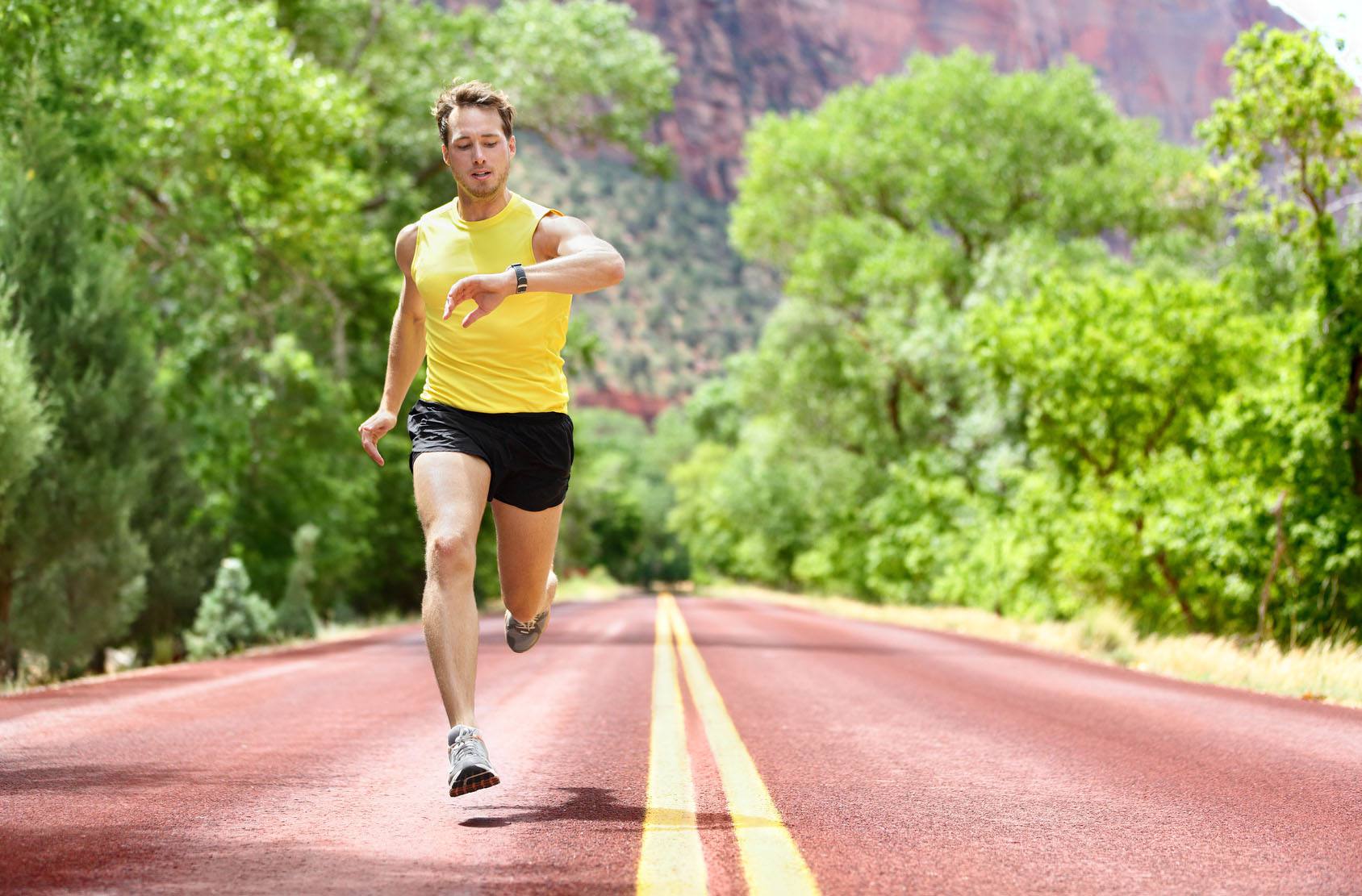 A man jogging on the road with a fitness tracker