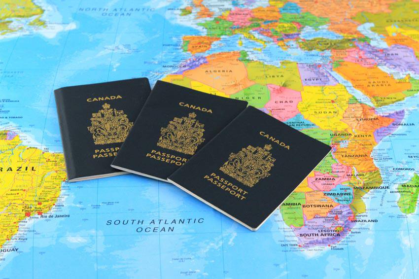 Three canadian passports spread on top of the world map