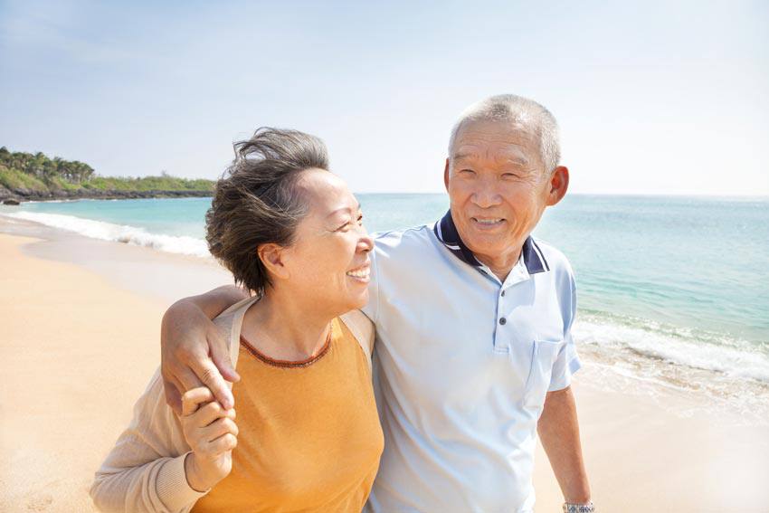 An elderly couple walking on the beach together