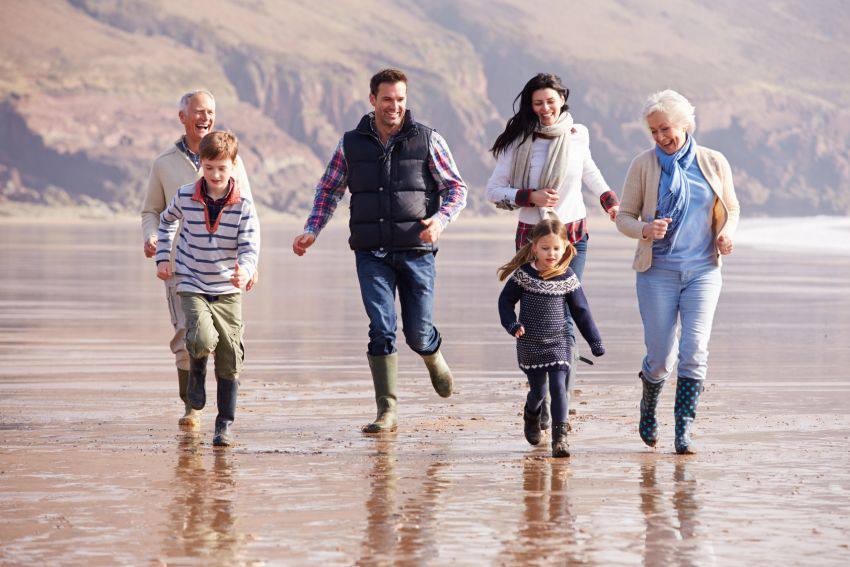 A family of six having fun running on the beach