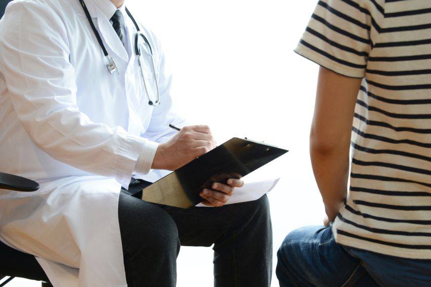 Doctor writing notes during a consultation with a patient