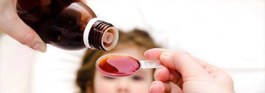 Medicine poured in a spoon in front of a sick child