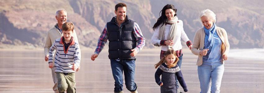 A family of six having fun running on the beach