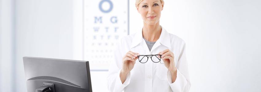 An optometrist in their office holding glasses