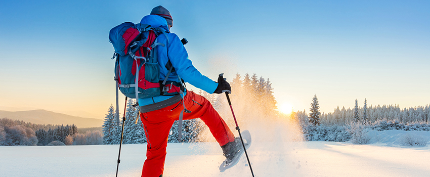 A person hiking in the snow with proper equipment