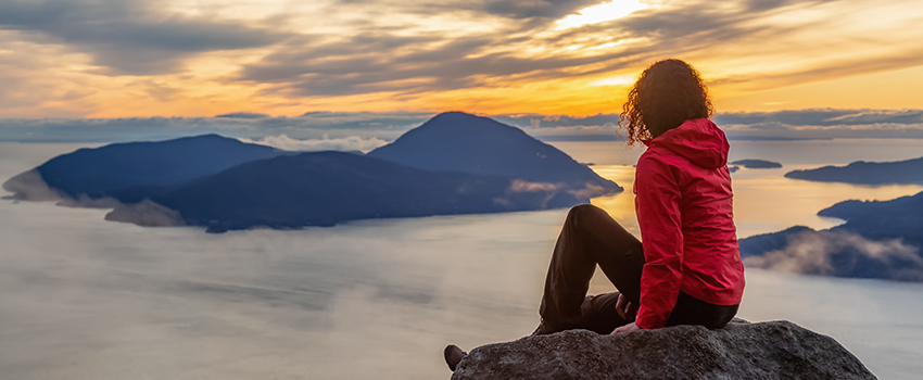 A woman sitting at the top of a mountain