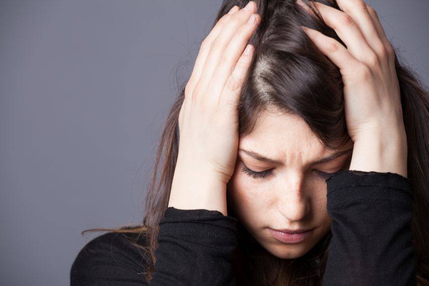 A woman holding her head in her hands with a sad expression