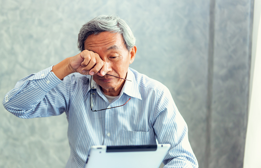 A man with glasses in his hands wipes his eyes