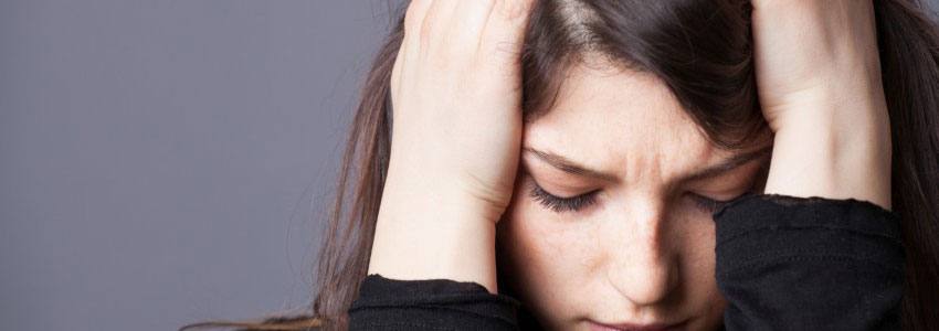 A woman holding her head in her hands with a sad expression