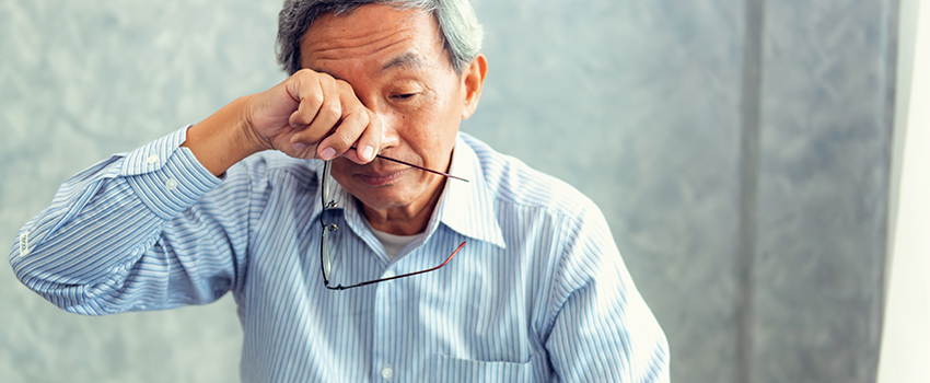 A man with glasses in his hands wipes his eyes