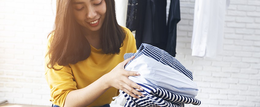 A young woman puts clothes in a box