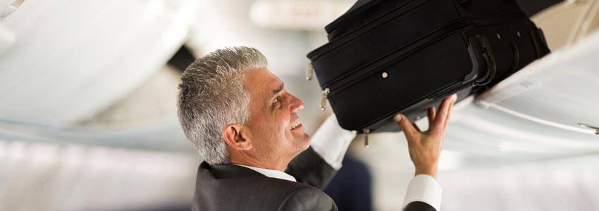 A person putting his suitcase in the compartment of airplane