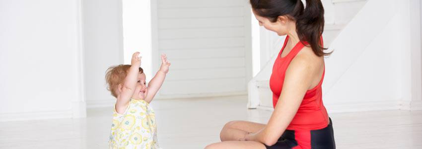 A woman and her baby sitting on a yoga mat