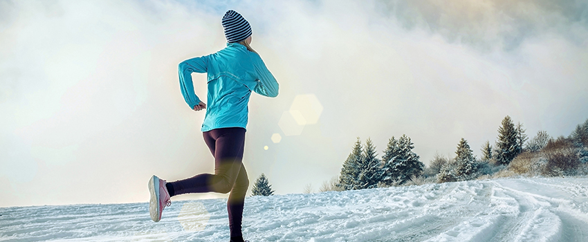 A lady runs in the snow in winter