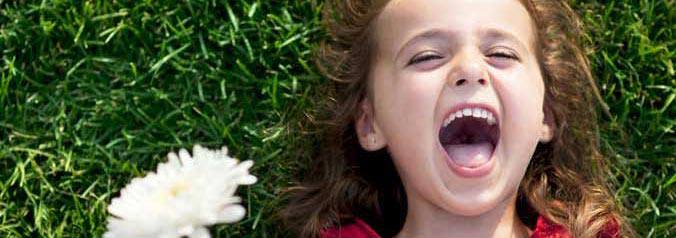 A little girl laughing holding a flower