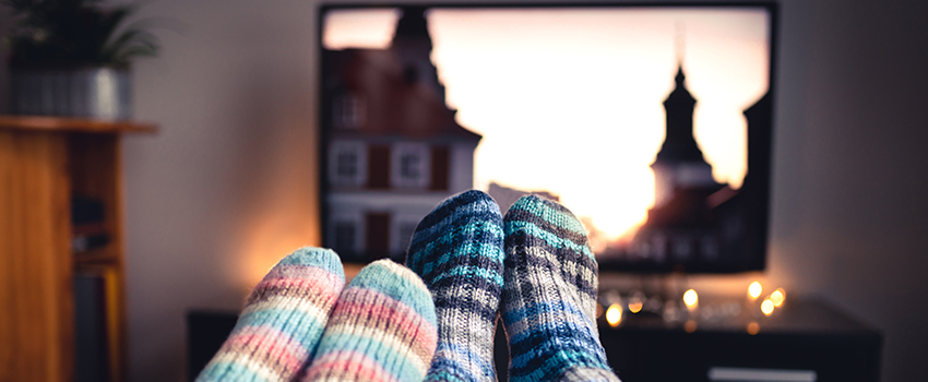 Two people watching television with their feet touching