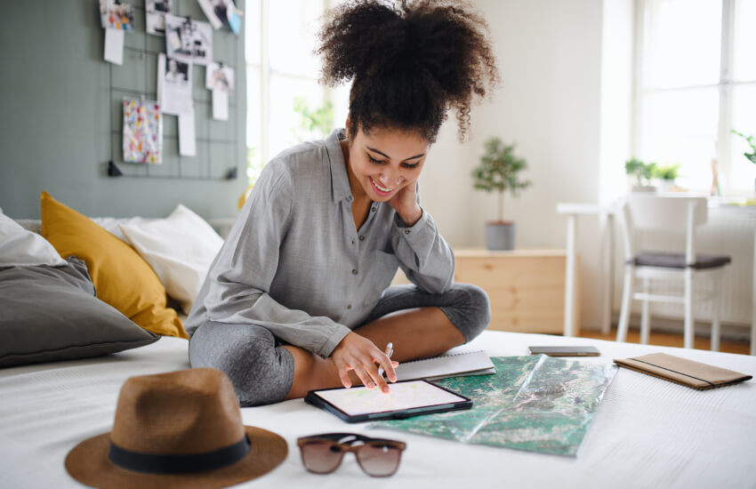 smiling woman sitting on her bed looking at her notebook