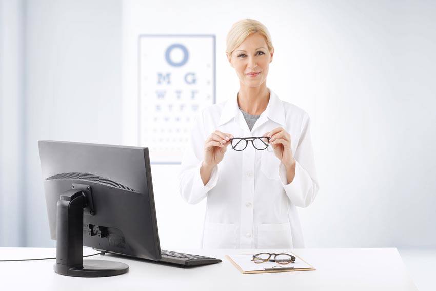 An optometrist in their office holding glasses